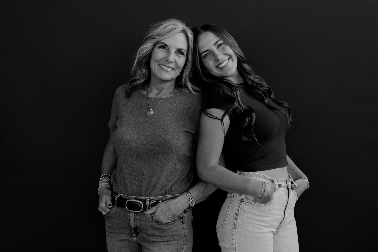Two women in casual clothing having fun during a studio photoshoot.