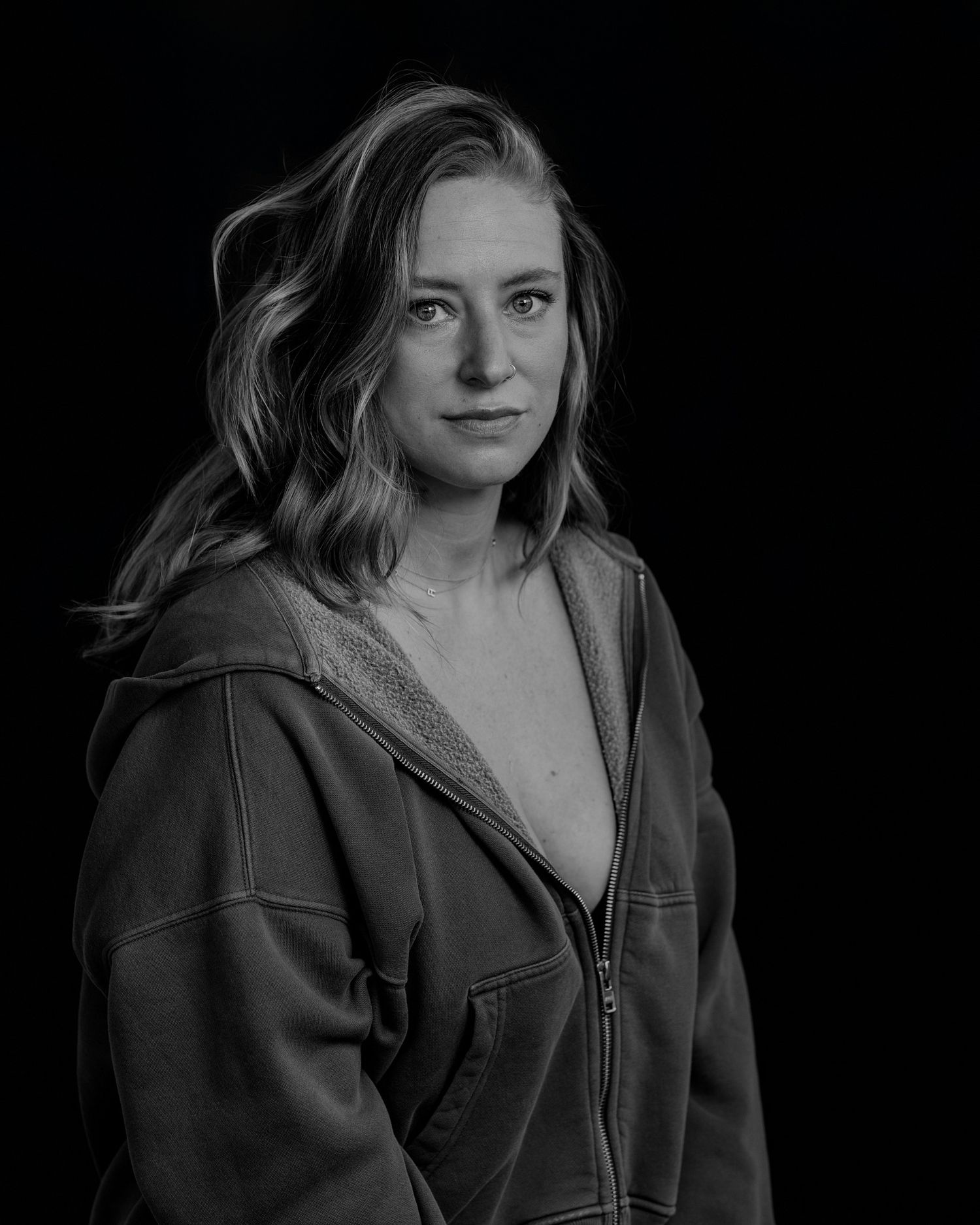 Dramatic black and white portrait with dark background showing figure in leather jacket.