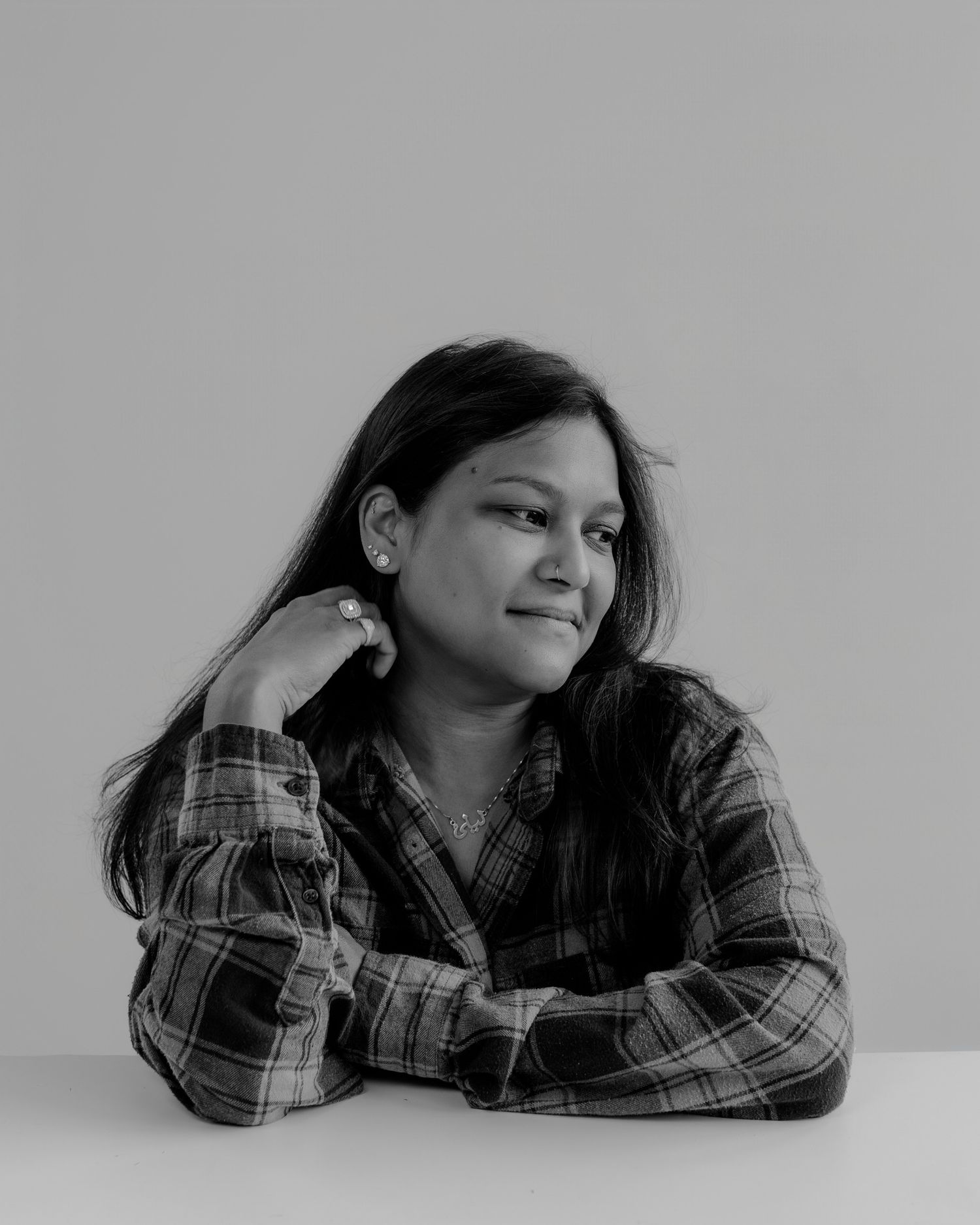Person wearing plaid shirt poses while lying down in artistic black and white series.