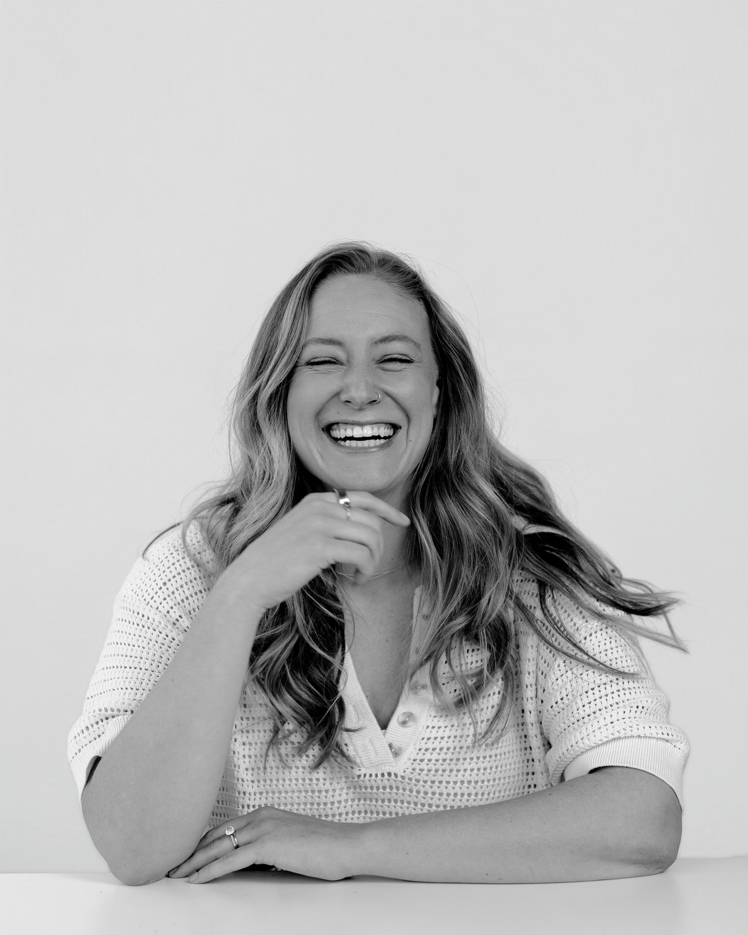 Person wearing white top showing series of laughing expressions in monochrome.