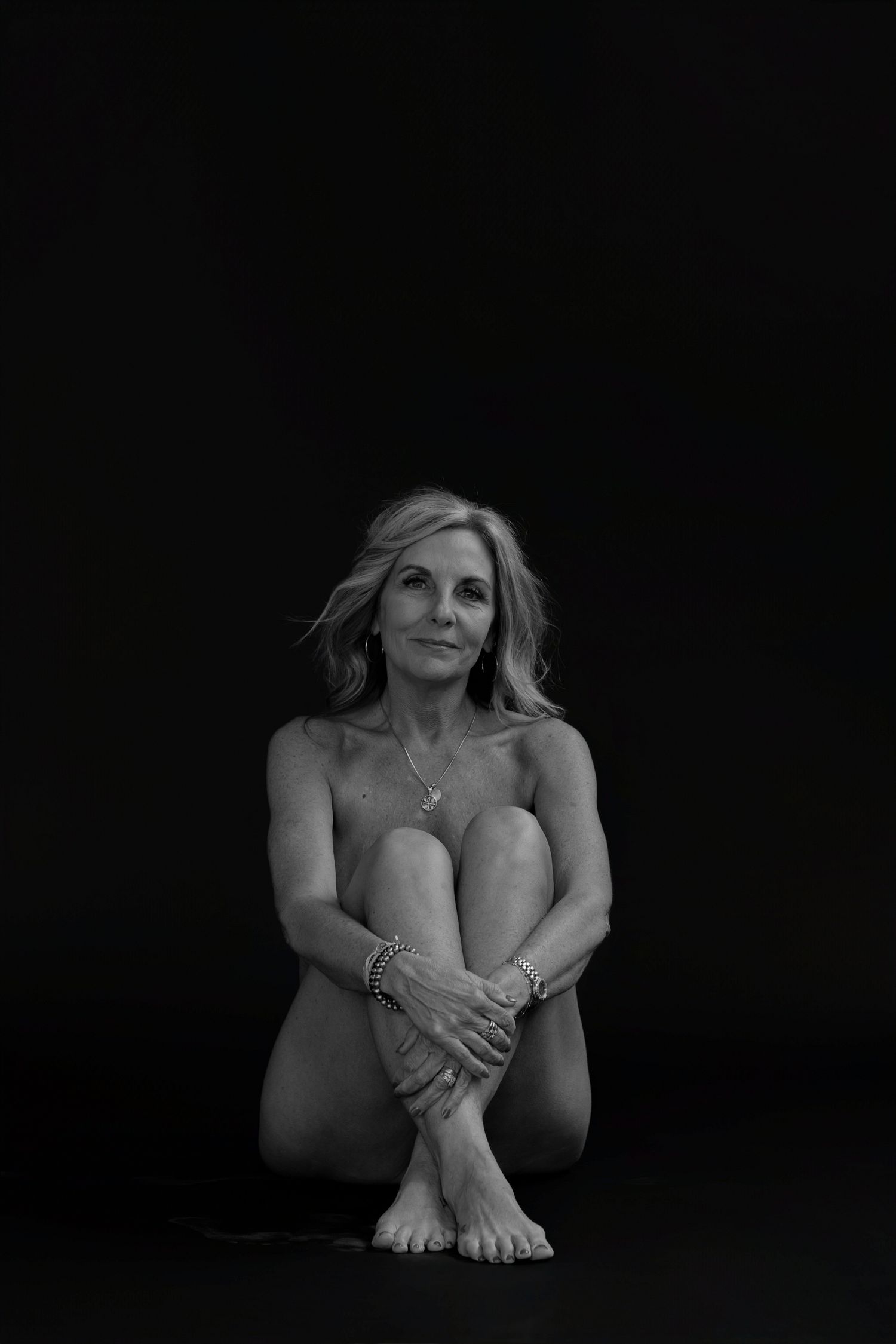 Intimate black and white portrait series showing natural poses against dark background.