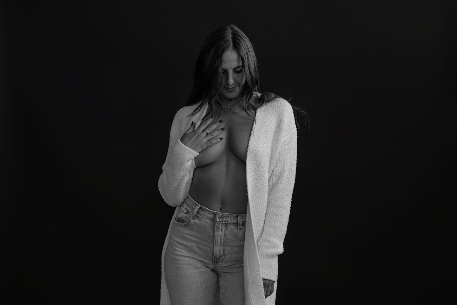 Fashion portrait featuring white cardigan and denim in dramatic black and white lighting.