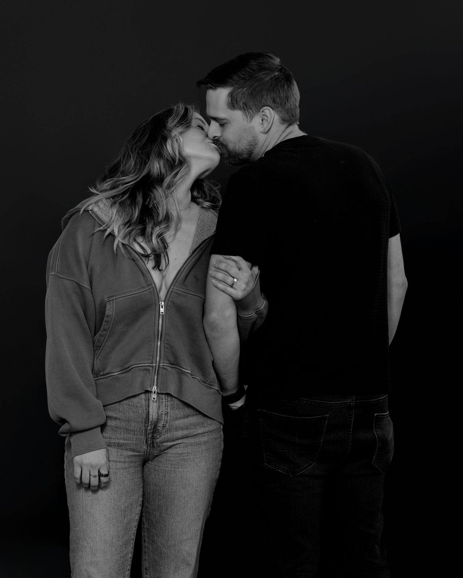 Romantic couple embracing in monochrome photo session wearing casual denim and black attire.