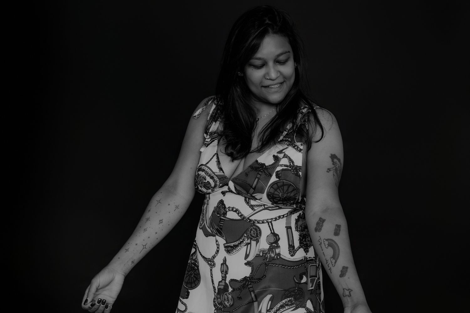 Casual portrait with someone wearing a sleeveless floral top in dark lighting.