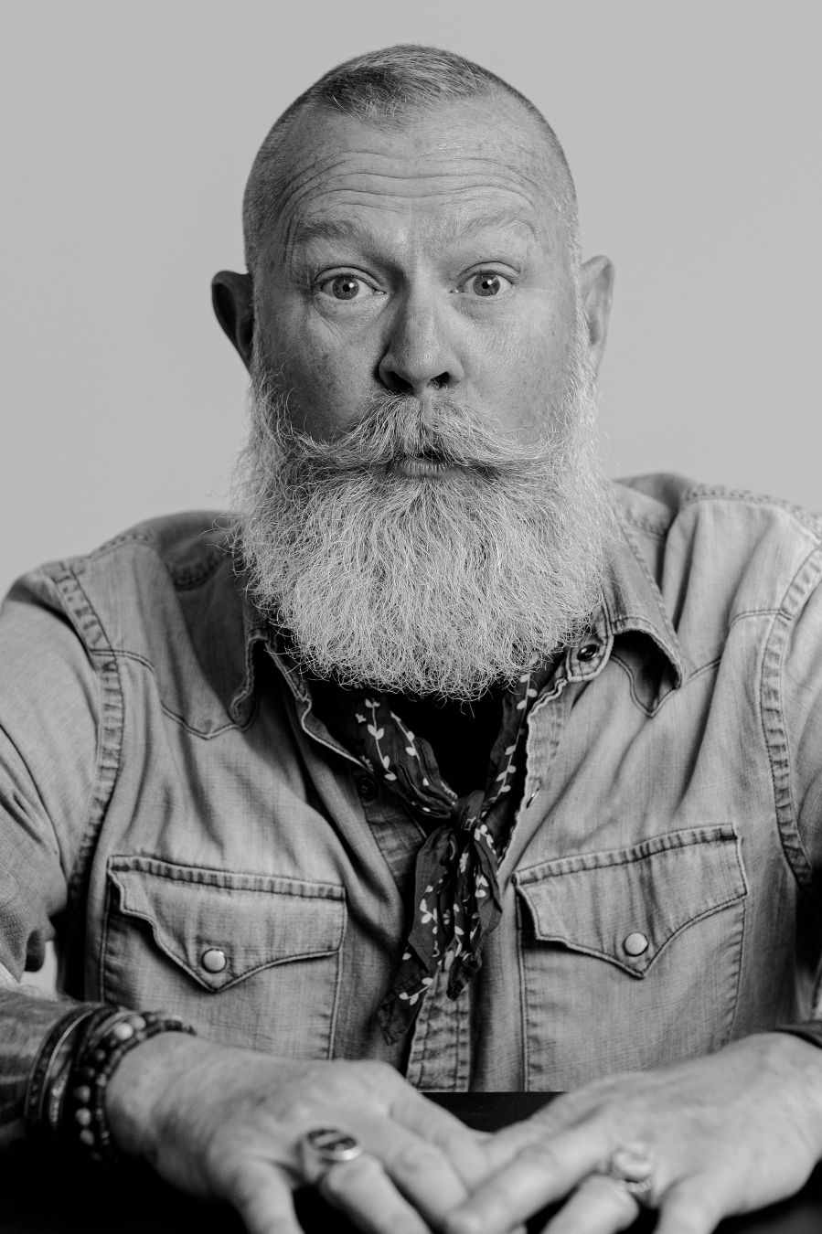 Black and white portraits of a bearded person in denim jacket showing various expressions.