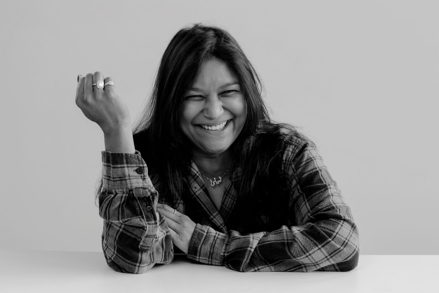 Individual in plaid shirt showing joyful poses while resting on table.