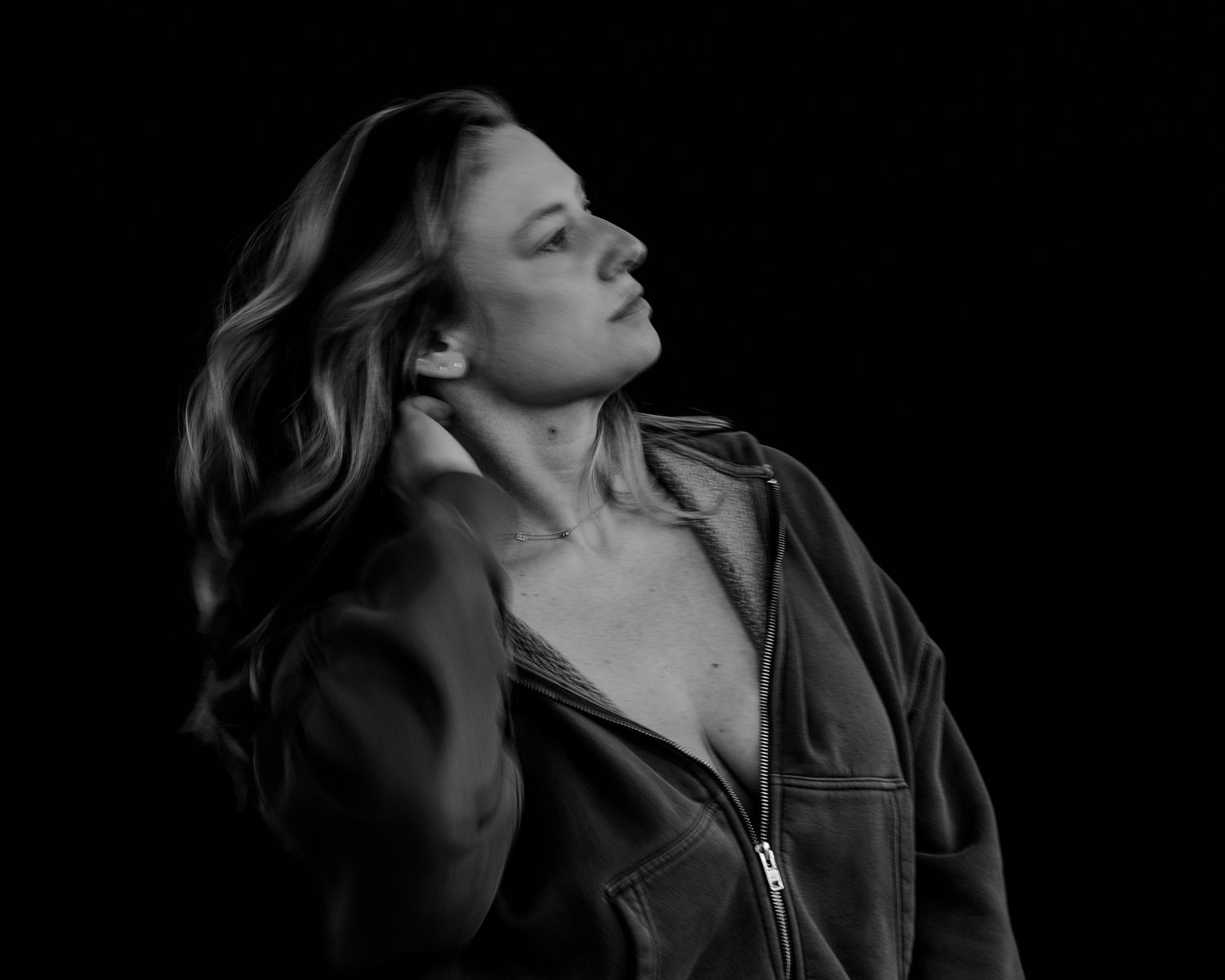 Artistic profile shot with figure in dark clothing against black backdrop.