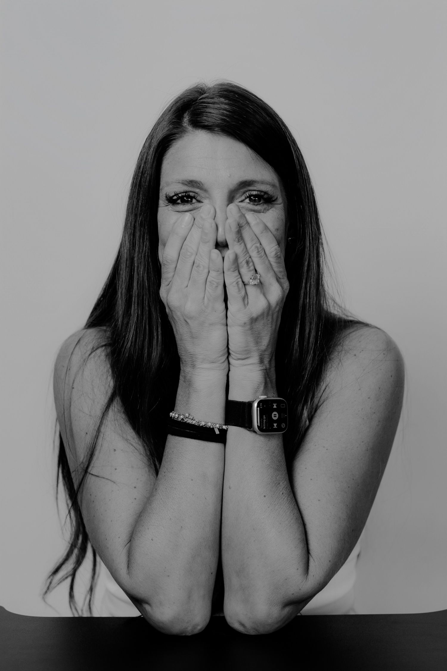 Black and white photo series showing hands covering face in progression of hiding behind palms.