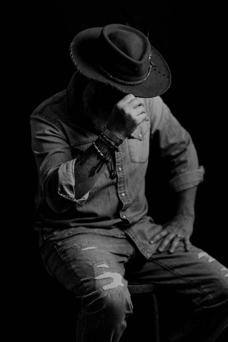 Low-key portrait series of person in hat and denim clothing.