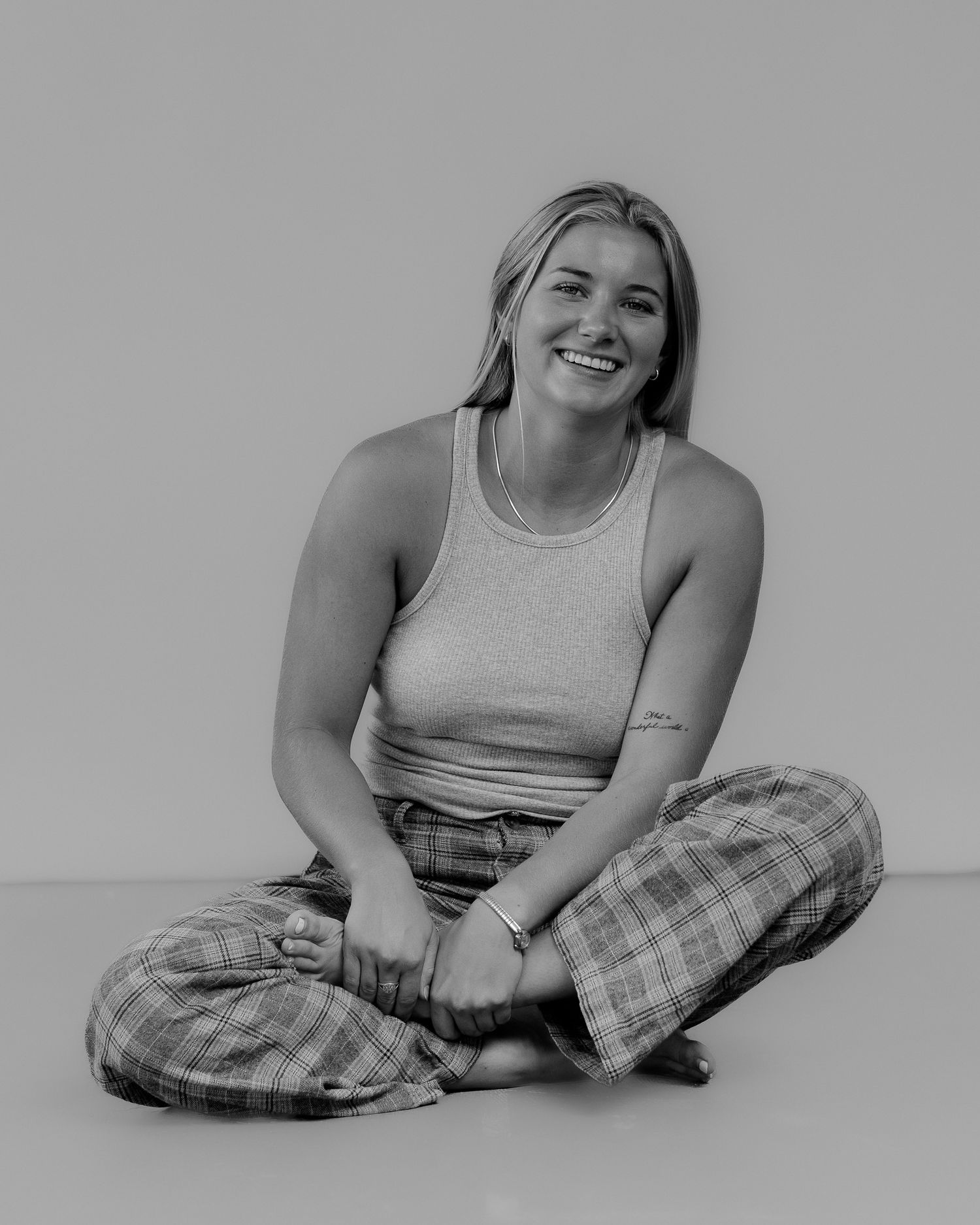 Person in casual attire sits cross-legged on floor in grayscale photo series.