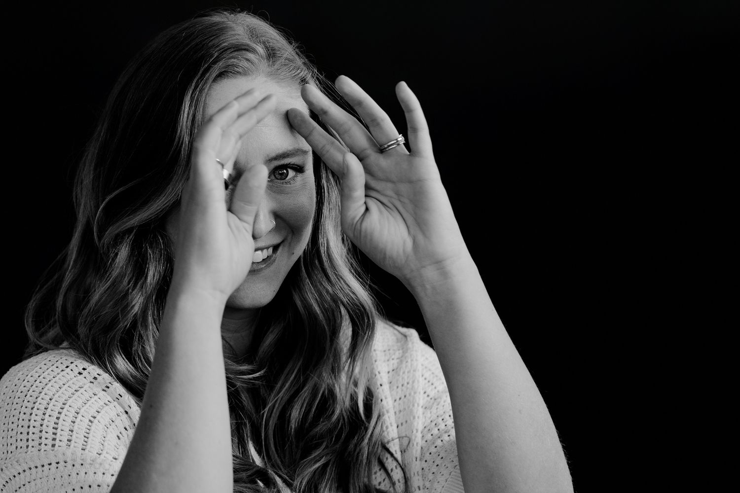 Black and white photo series showing someone playfully hiding their face behind their hands in various poses.