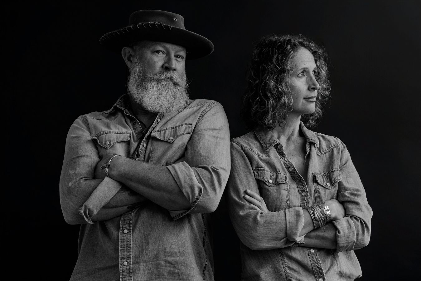 Black and white portraits showing intimate embraces and tender moments between couples in a dark studio setting.