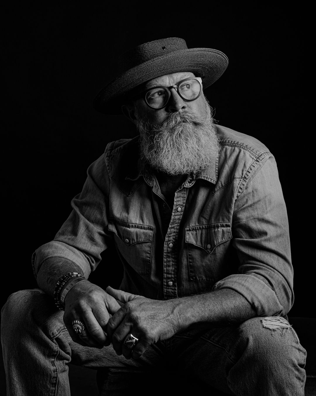 Artistic black and white portrait featuring glasses, hat and full beard in western style.