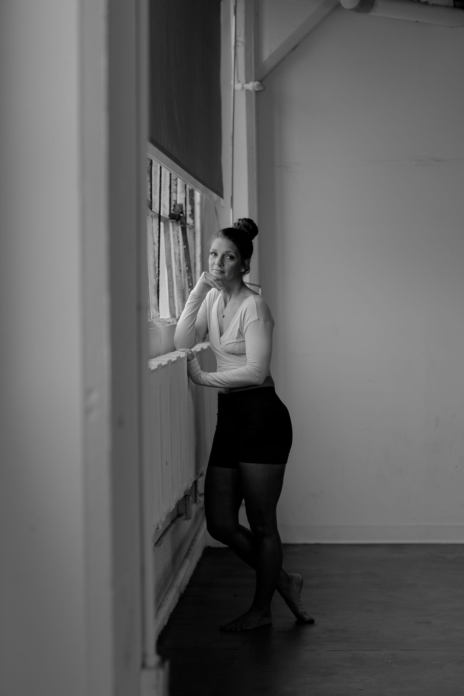 Atmospheric dance poses near windows in a minimalist studio space.