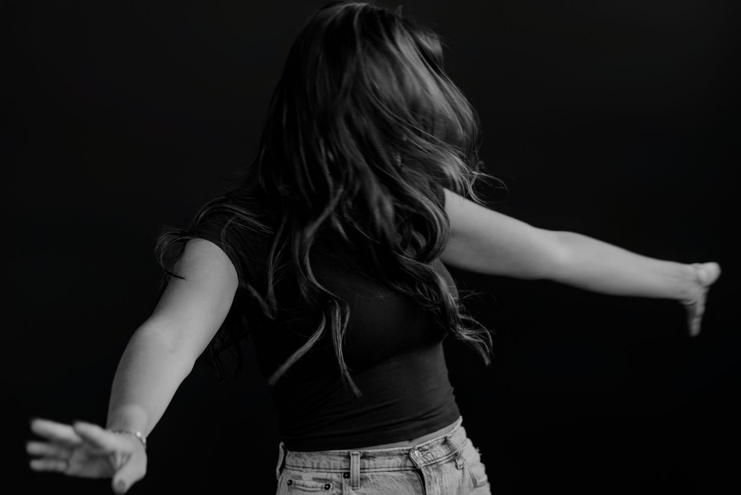 Artistic motion capture of person dancing with arms outstretched in black and white.