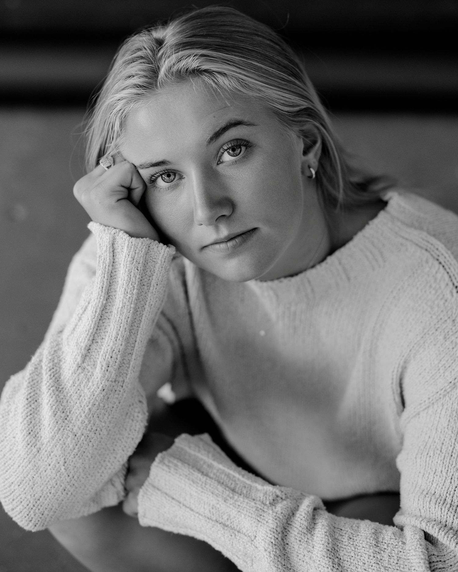 Black and white portrait series showcasing contemplative poses in a white sweater against a light background.