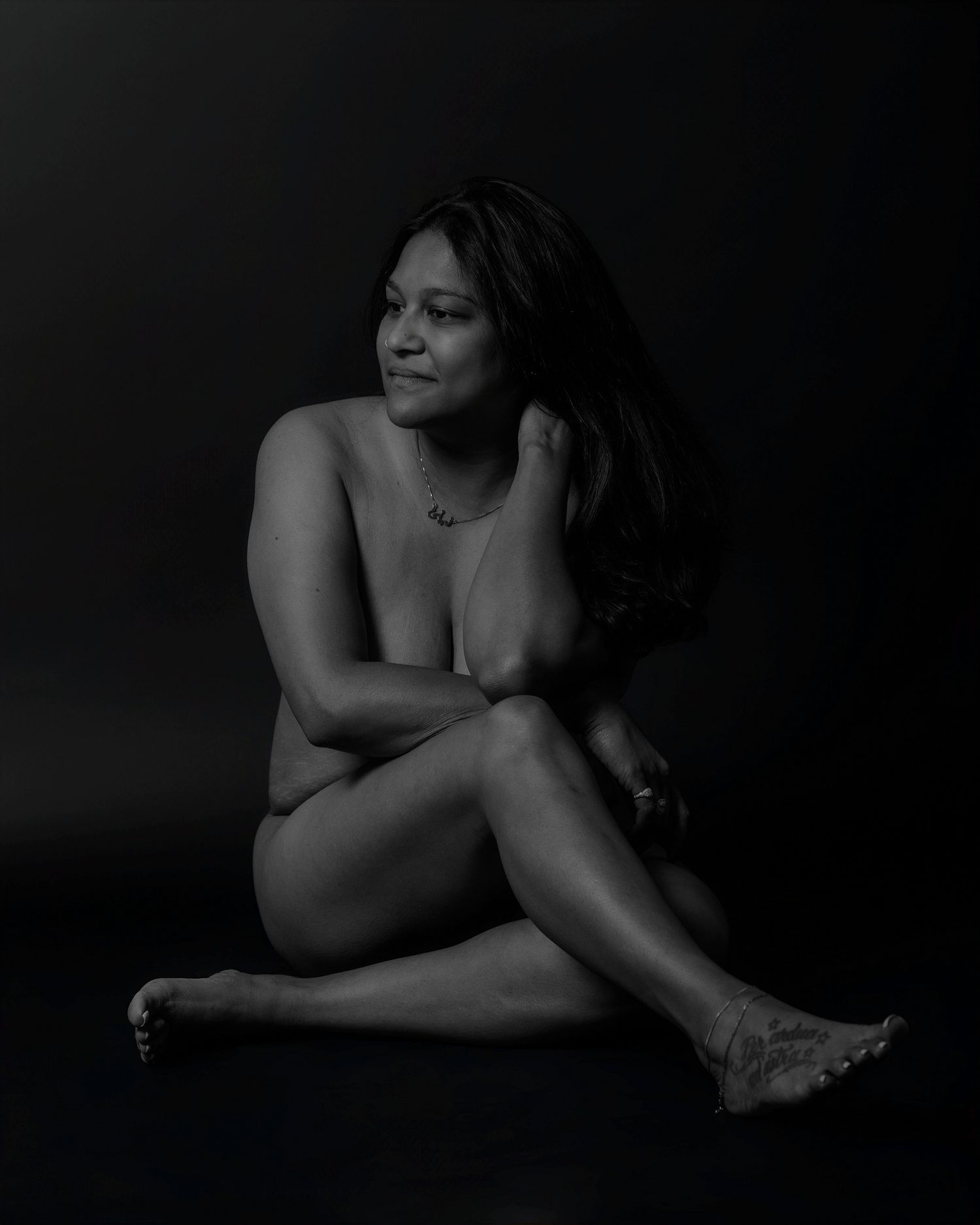 Artistic black and white studio portrait showcasing intimate pose and natural lighting.