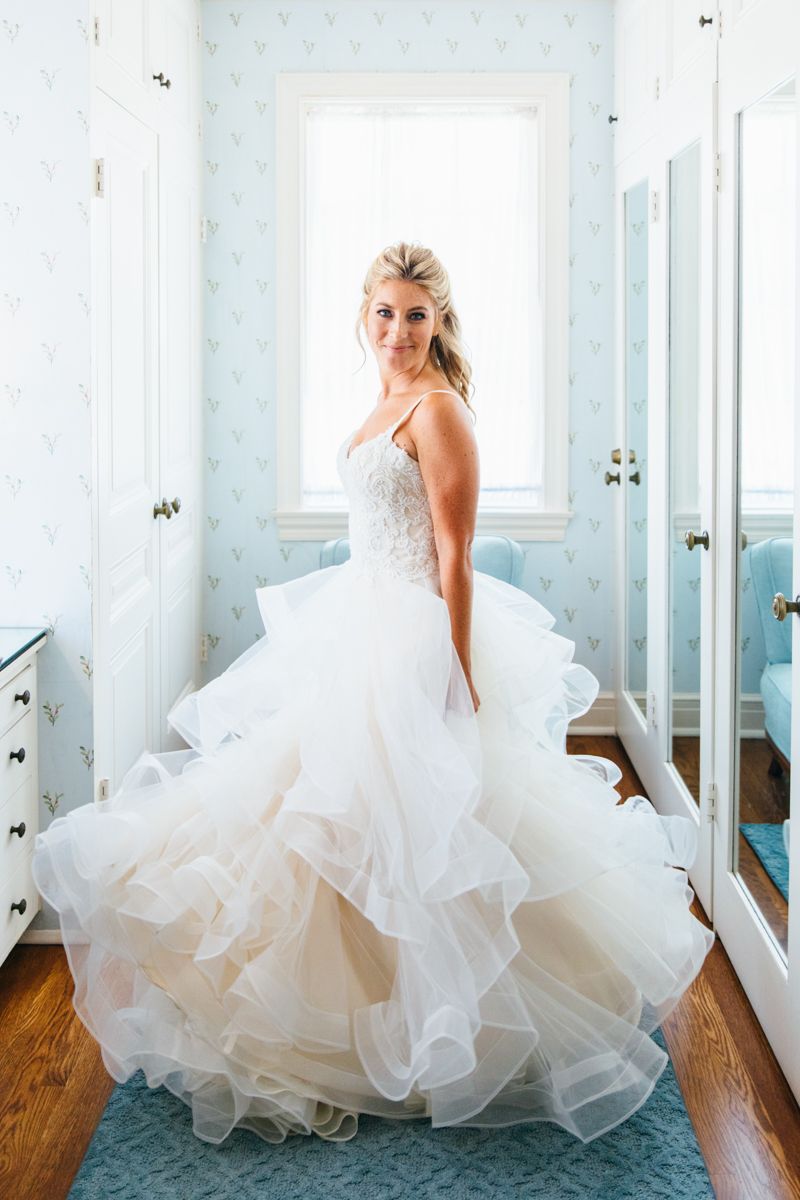 Bride in a stunning ruffled ballgown wedding dress posing in a blue wallpapered dressing room.