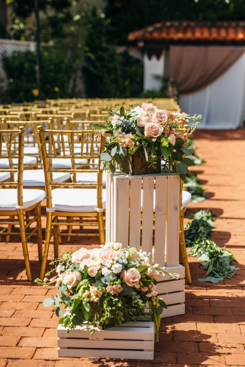 White wooden crate wedding aisle decor with blush pink roses and lush greenery bouquets.