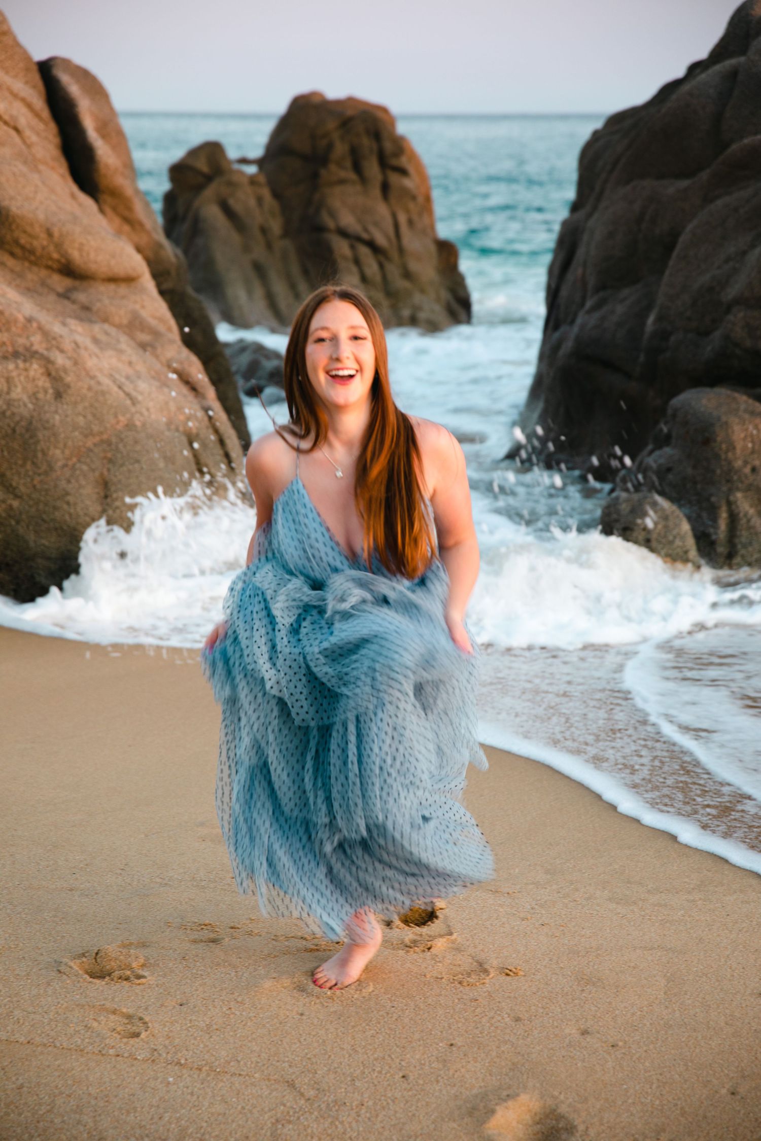 teenage girl running from waves in Cabo San Lucas