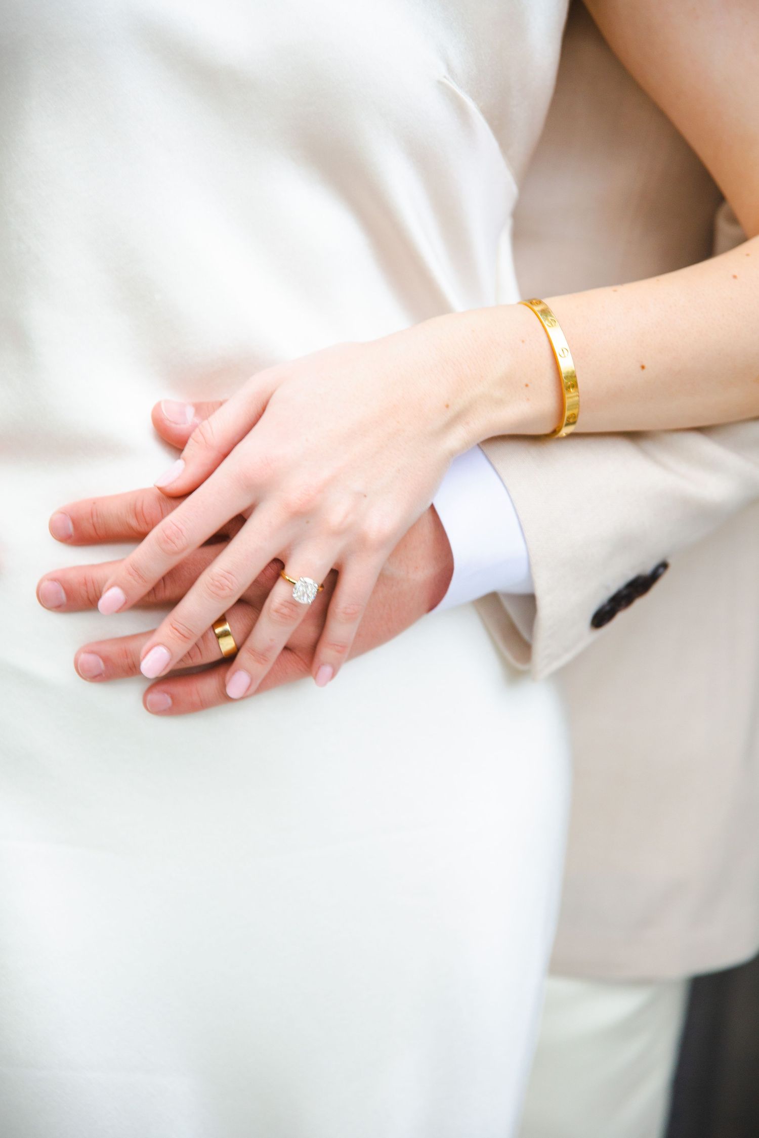A close-up of hands wearing a wedding ring and  in the background at an intimate wedding in Cabo at ACRE Resort