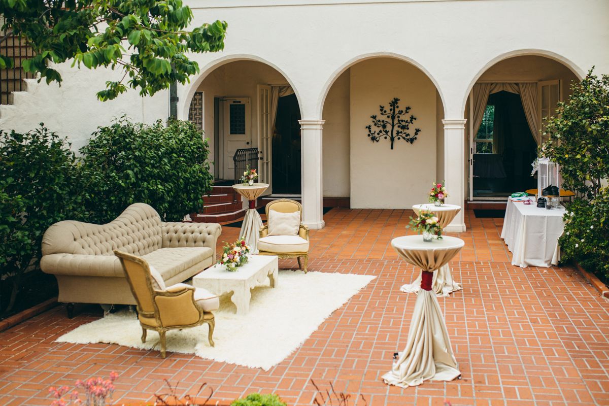 Elegant Spanish-style wedding venue courtyard with vintage furniture lounge seating and arches.