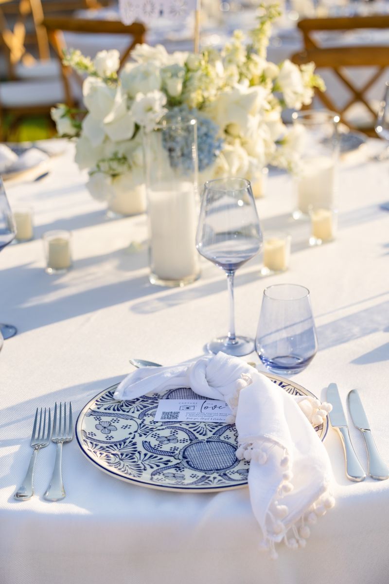 Blue and white patterned plate with linen napkin at elegant outdoor wedding reception table.