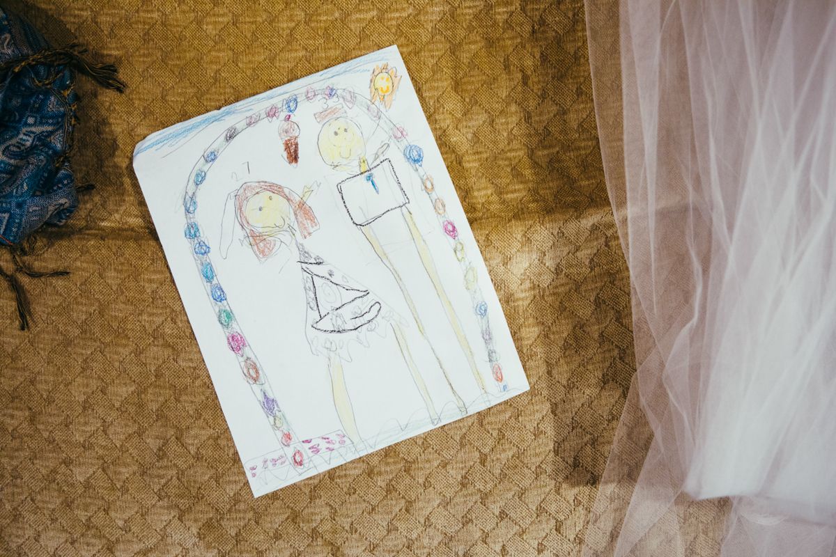 Child's crayon drawing of bride and groom displayed next to wedding veil.
