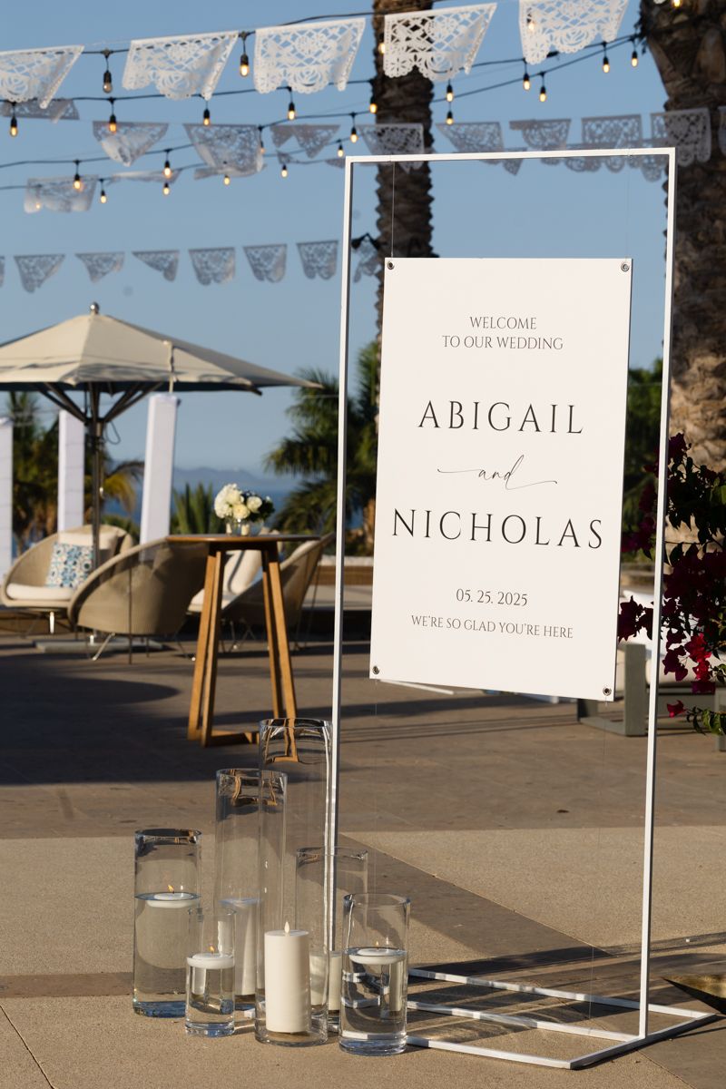 Wedding welcome sign for Abigail and Nicholas dated 05.25.2025 with candles outdoors.