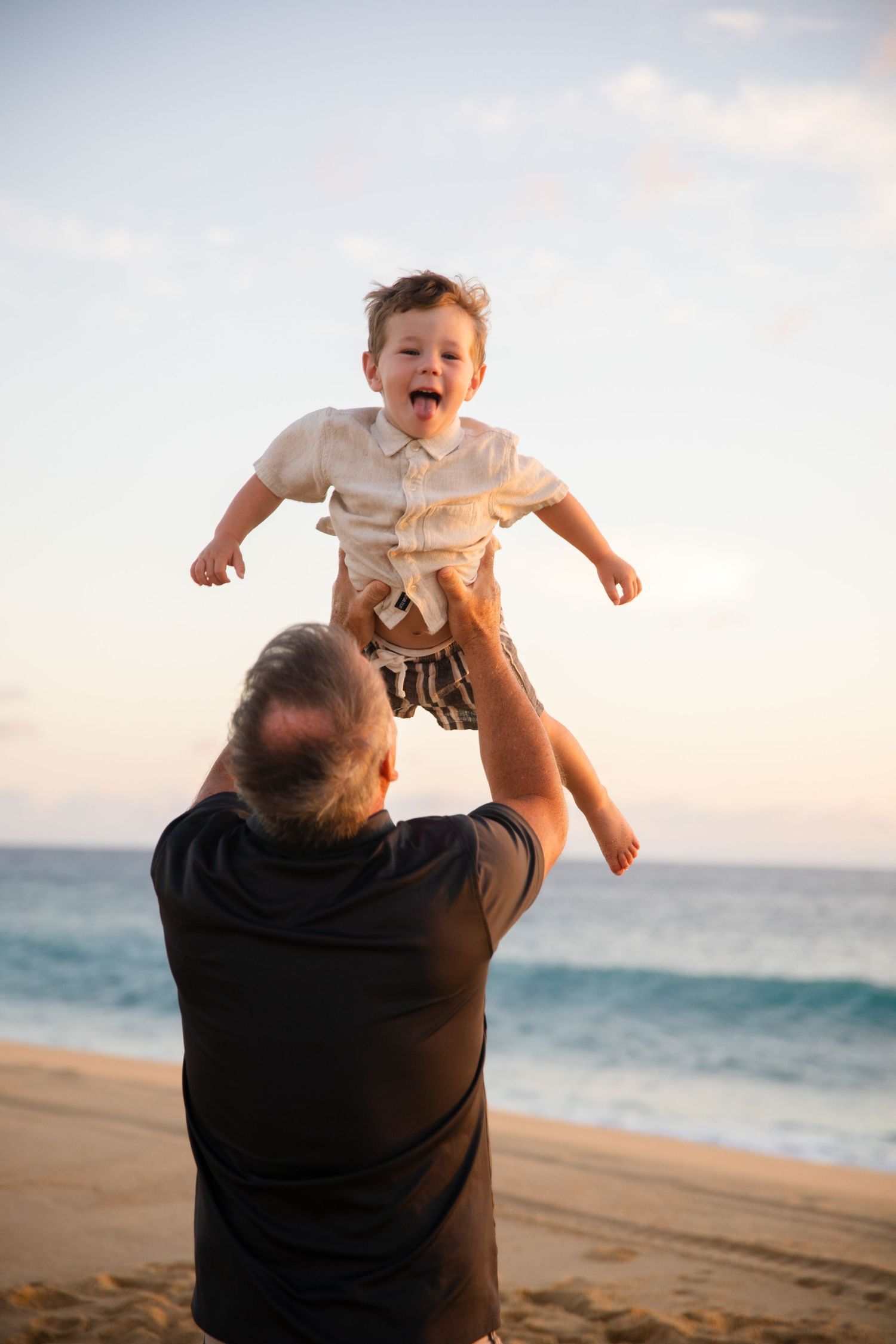 man tossing boy into the air on beach in Cabo San Lucas