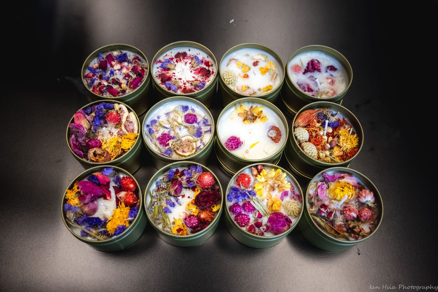 Multiple glass bowls filled with colorful flower petals arranged in a row on dark surface.
