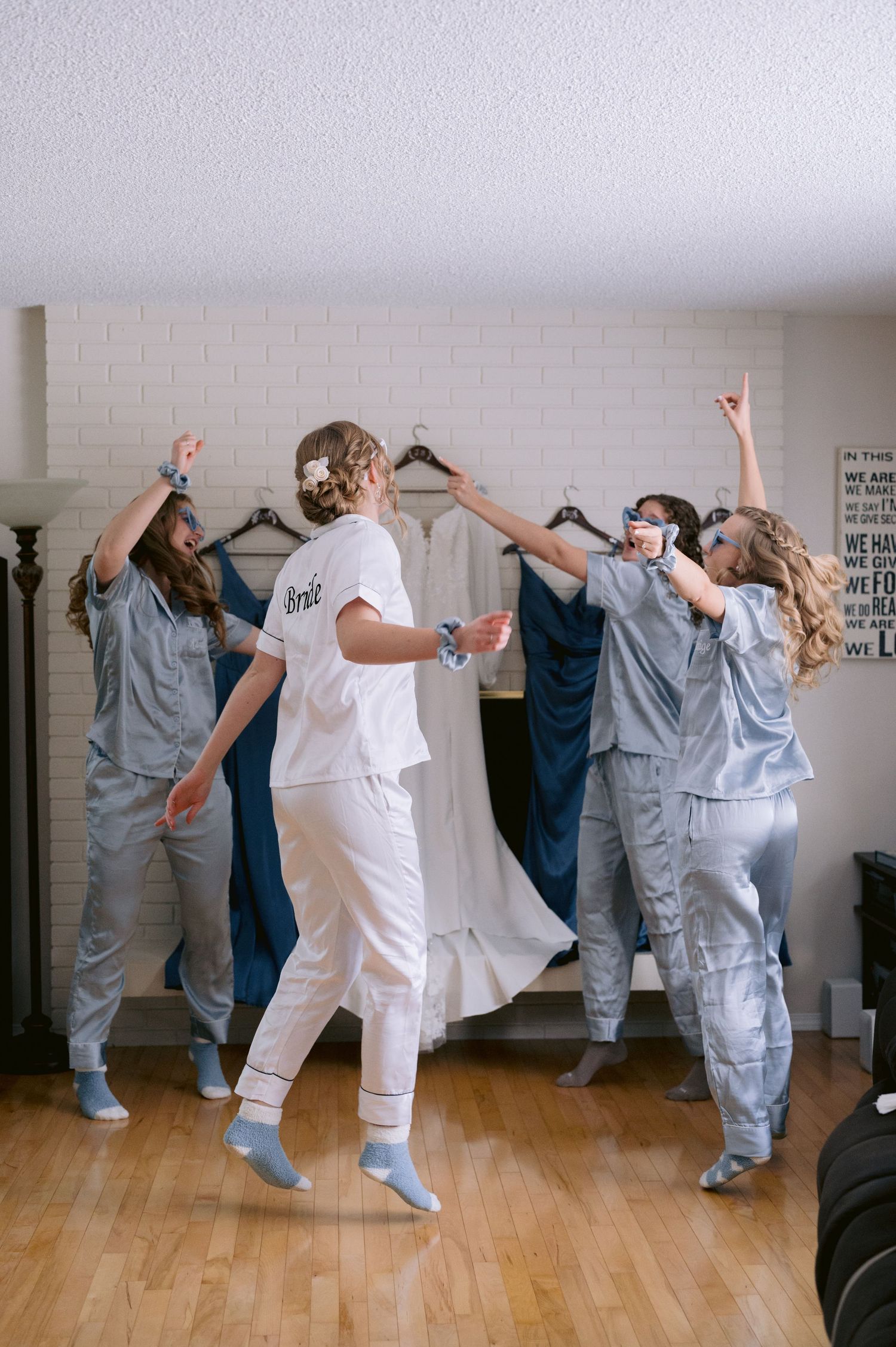 A group of dancers in gray jumpsuits and white outfits perform synchronized movements in a dance studio.