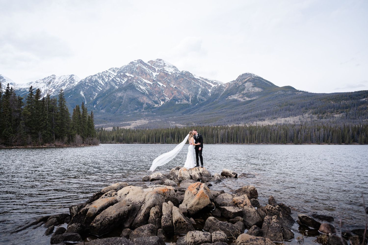 A panoramic mountain landscape with snow-capped peaks reflecting in a serene lake.
