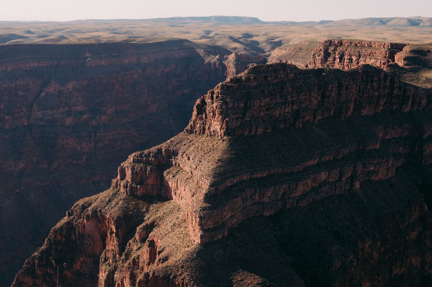 A scenic panoramic view of the Grand Canyon with red rock formations and layered cliffs stretching into the distance.
