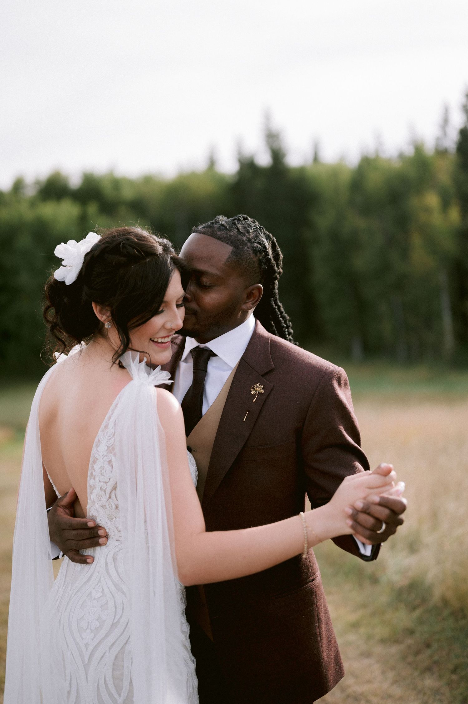 A tender moment between newlyweds sharing their first dance outdoors.