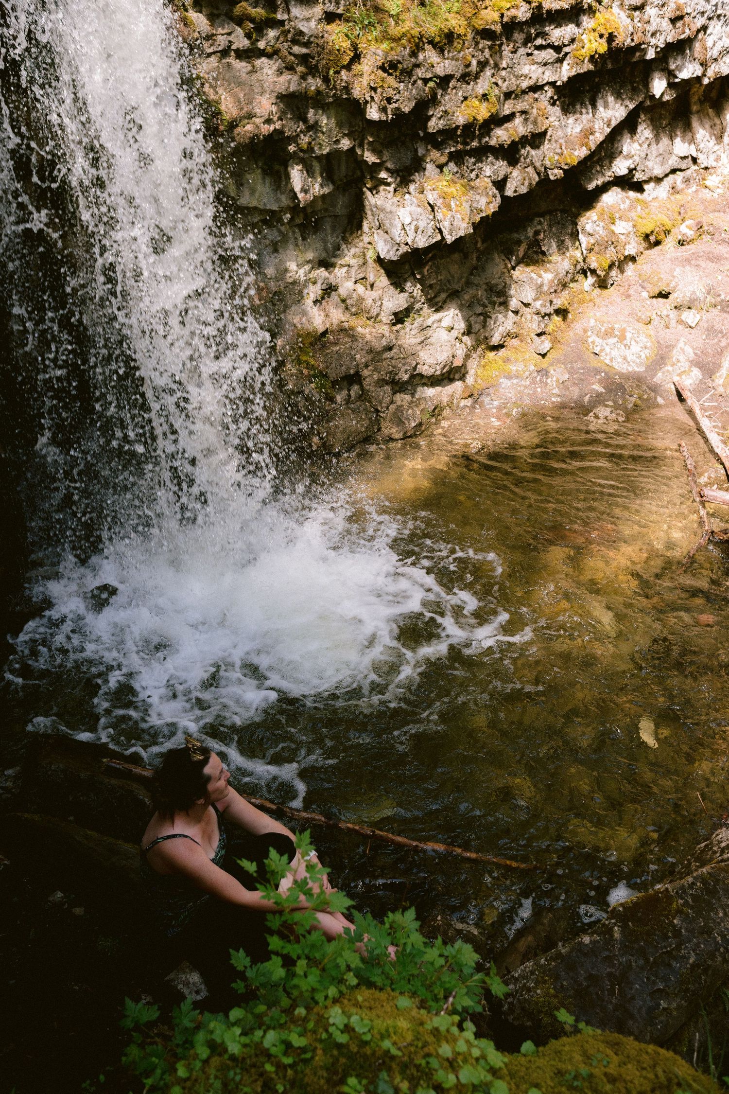 A sequence of images shows someone diving into a waterfall pool surrounded by rocky cliffs and lush green plants.
