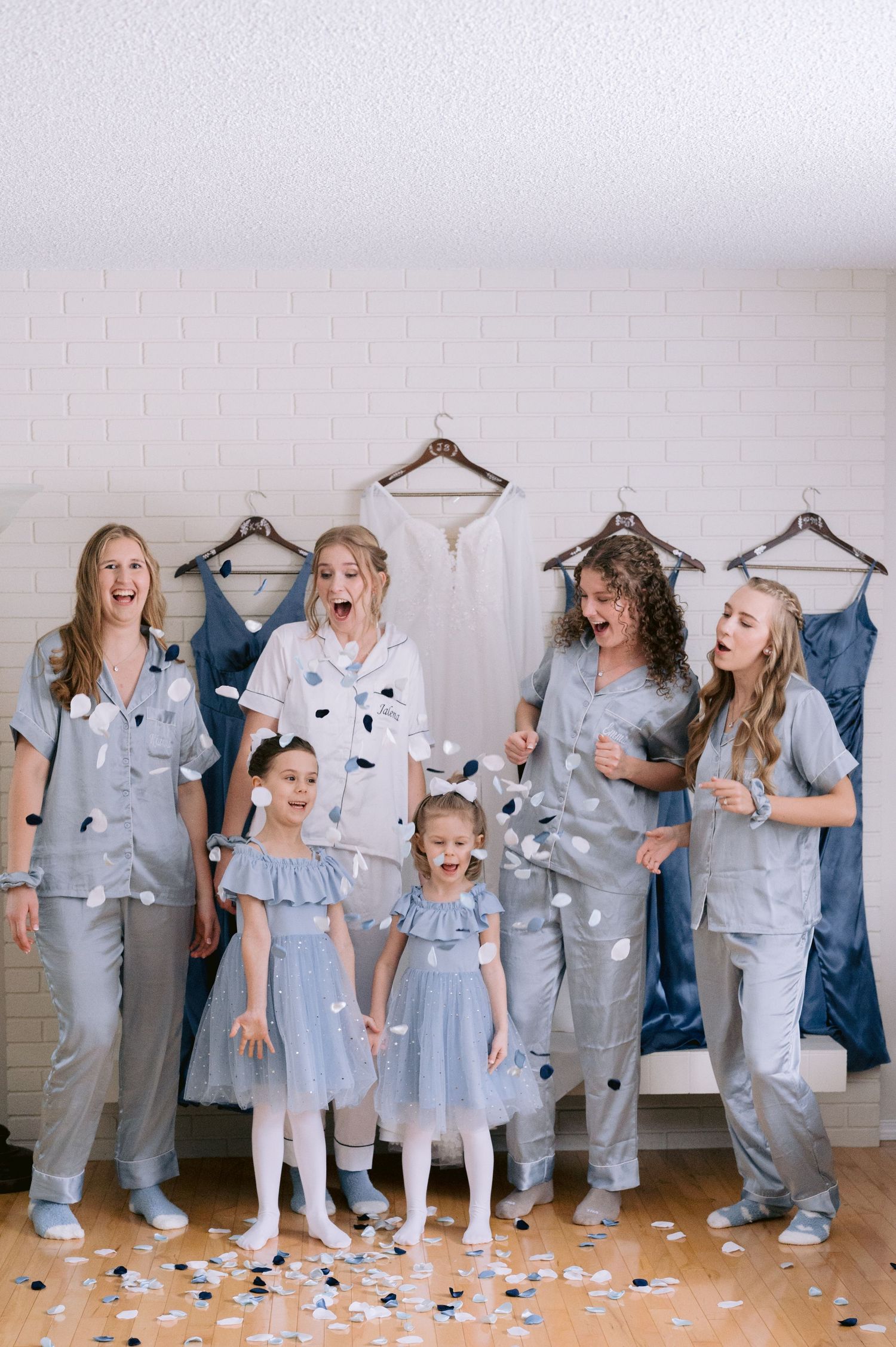 A group in matching light blue pajamas poses together as confetti falls in a playful indoor photoshoot sequence.