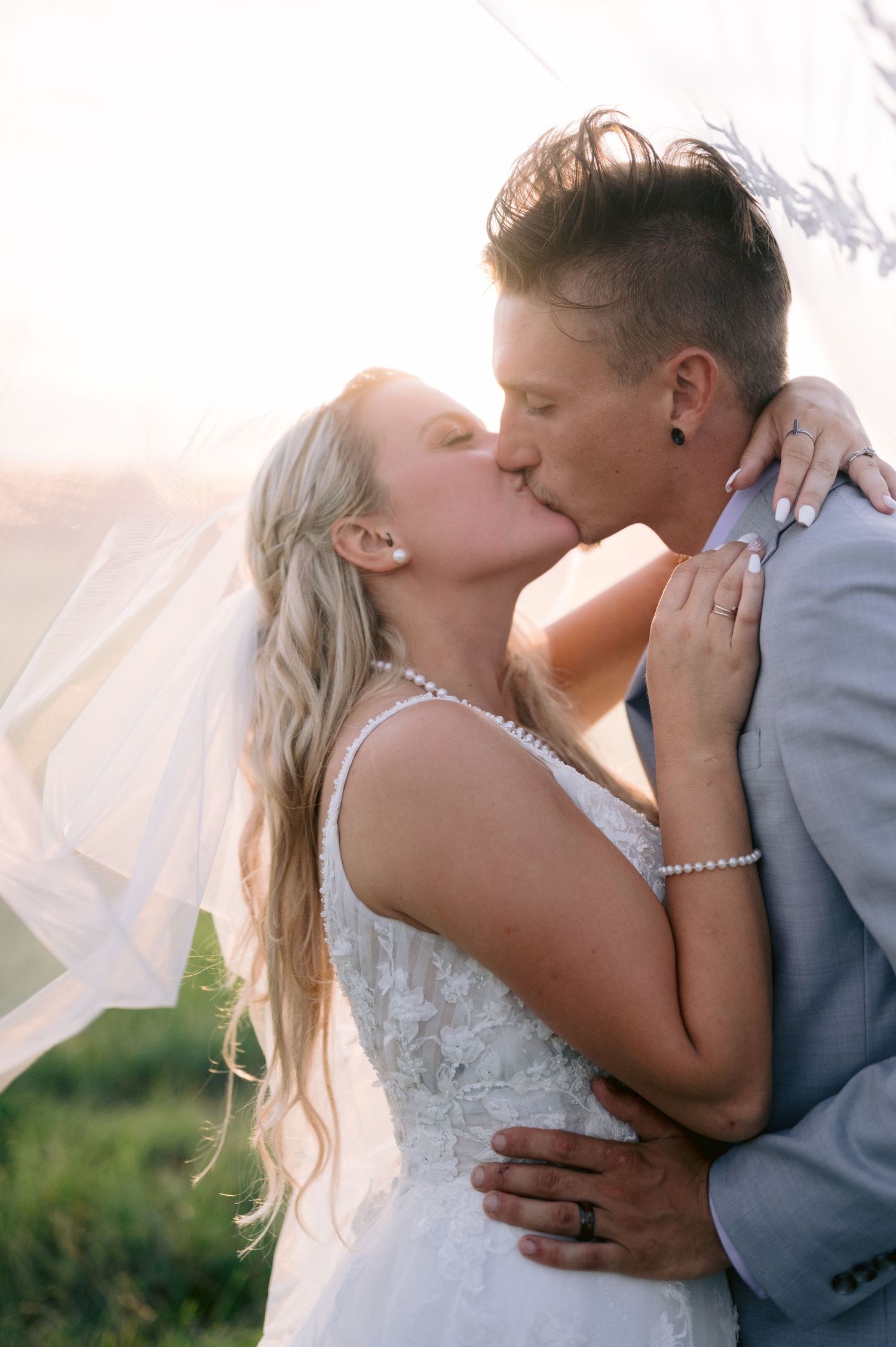 A romantic wedding couple sharing intimate kisses in a series of four connected photos outdoors at sunset.