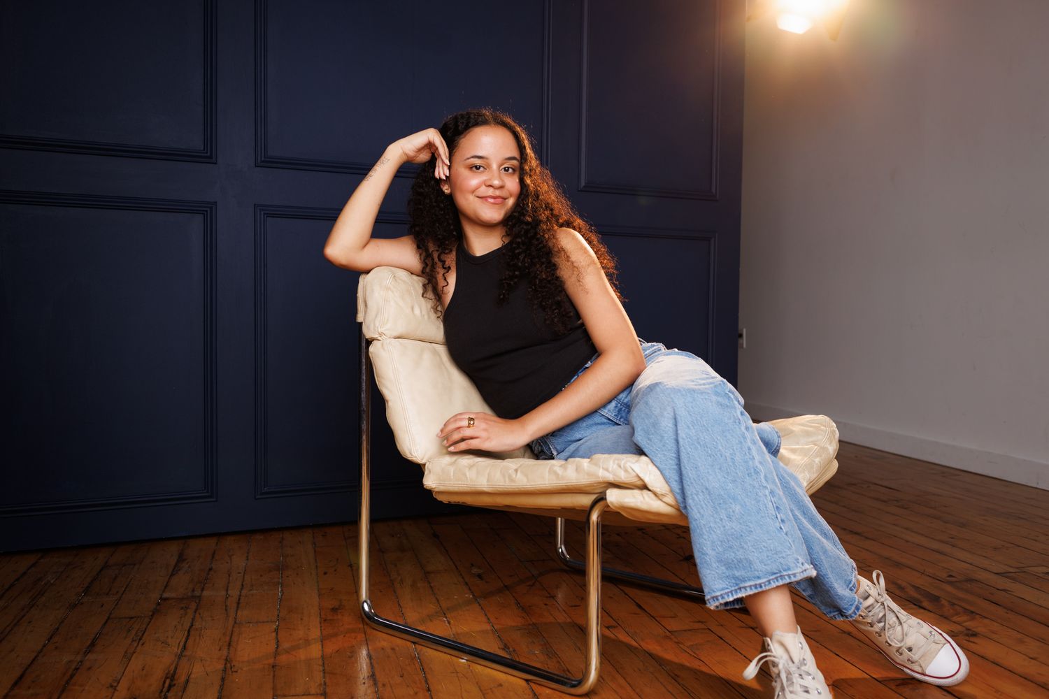 Lifestyle photo of someone sitting casually in a modern chair under warm lighting.