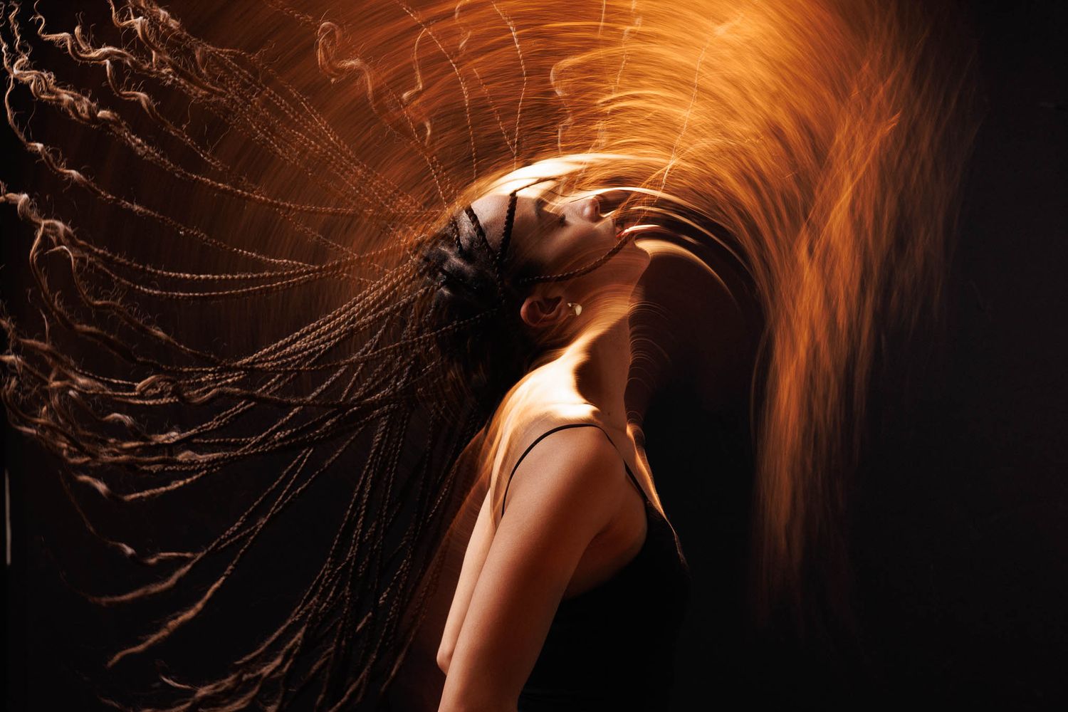 Creative portrait series showing flowing orange hair movement against black background.