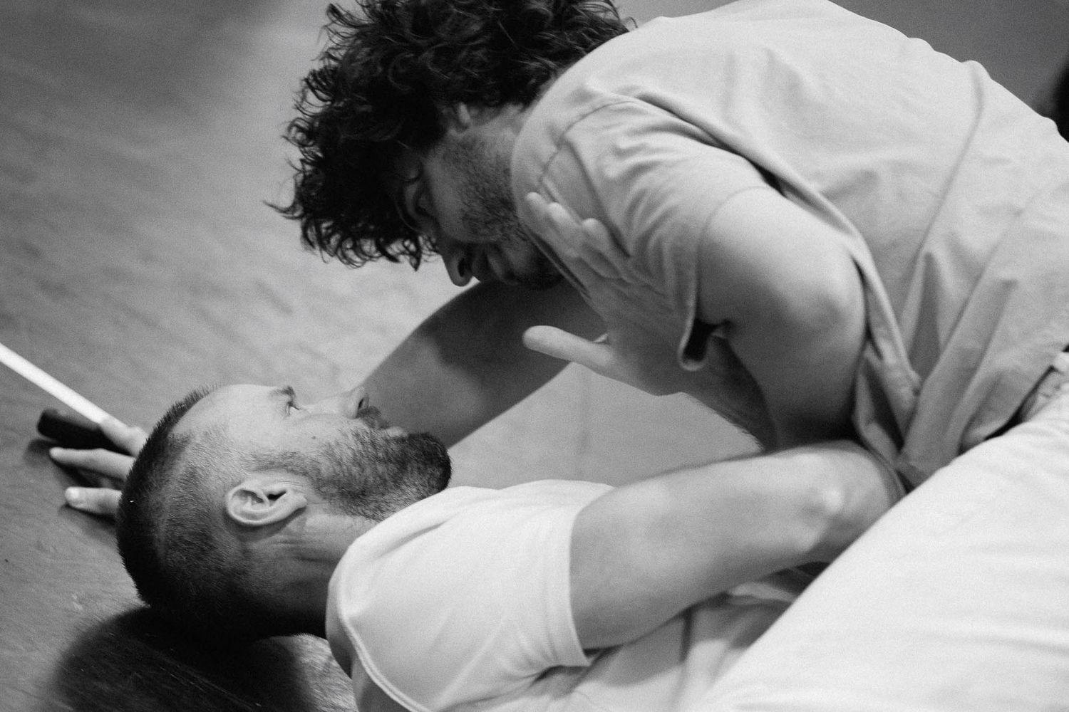 A dramatic black and white photo showing an intimate moment between two performers on stage.