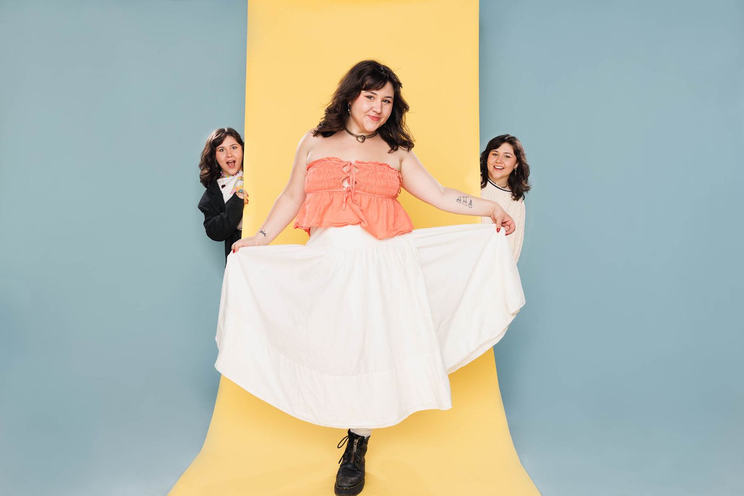Playful fashion photo with three people posing against colorful geometric backdrop.