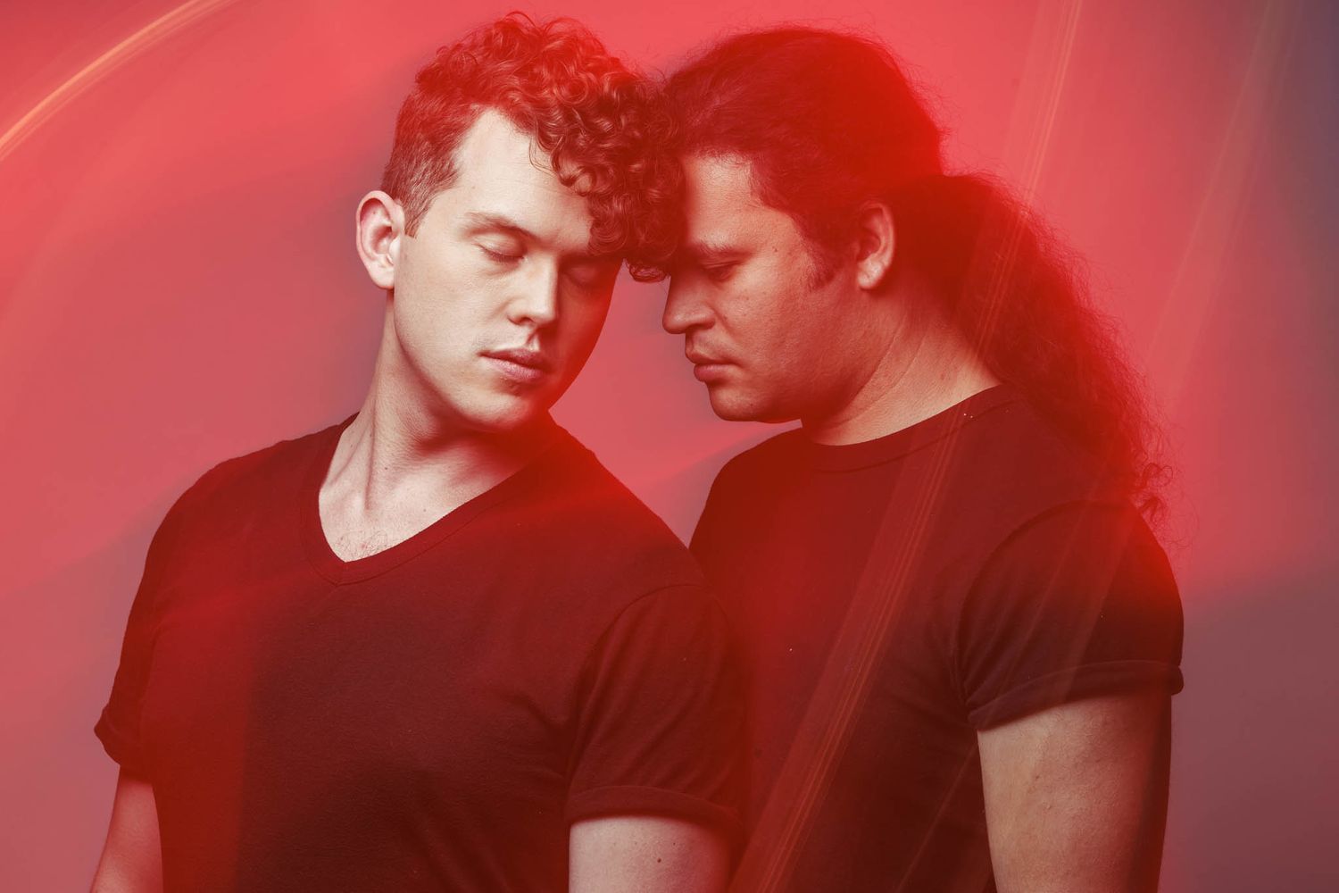Two actors bathed in moody red lighting creating an atmospheric portrait.