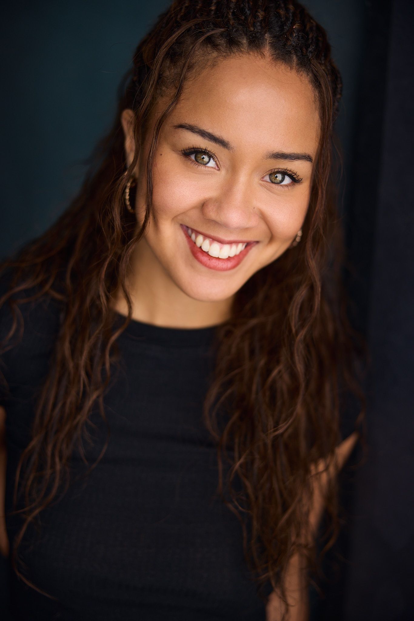 Portrait series showing bright smiles and expressions against dark background with black top and long dark hair.