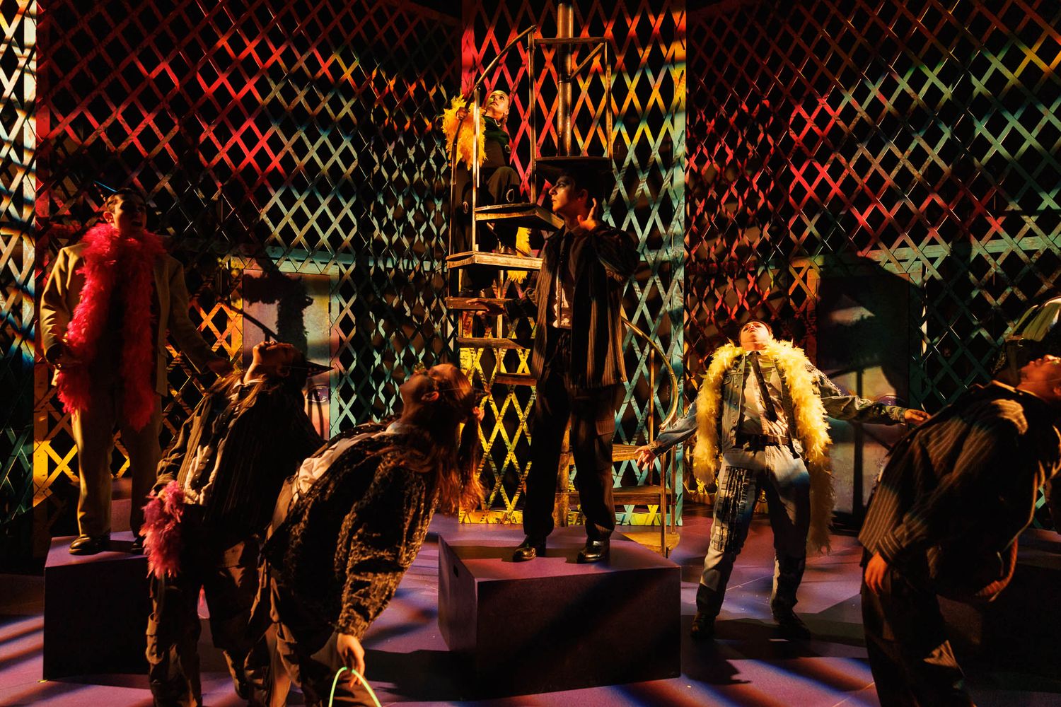 Energetic theater performance with actors in period costumes on a latticed set with red lighting.