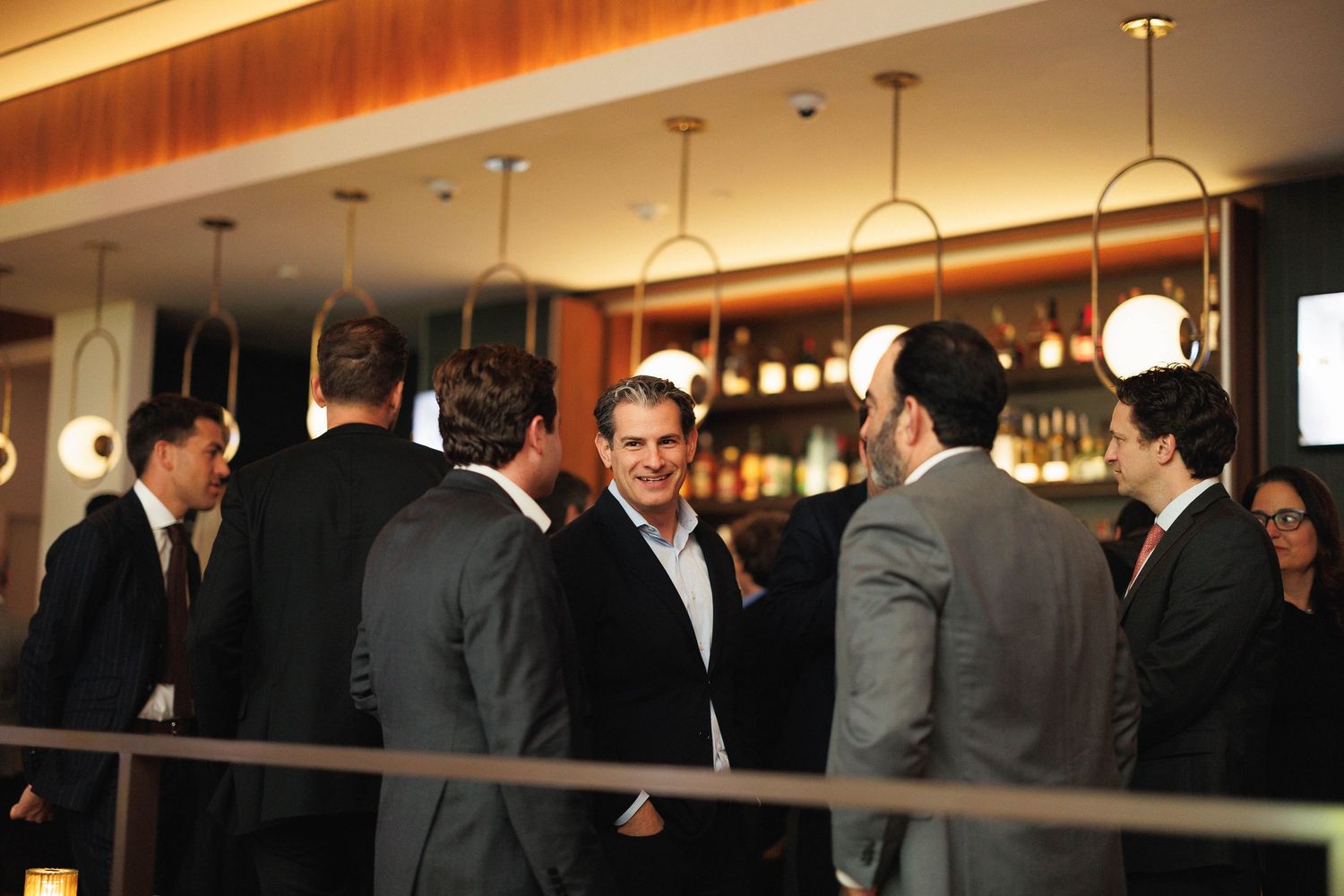 Business professionals network and socialize at an upscale bar during a corporate event.