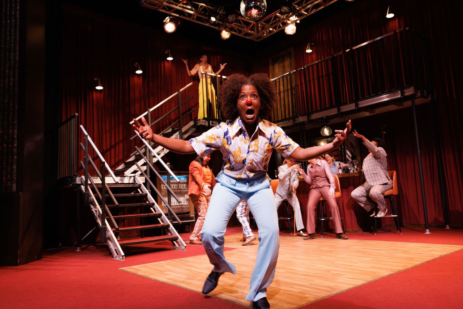 Energetic performer dances on stage in denim outfit during theatrical production.