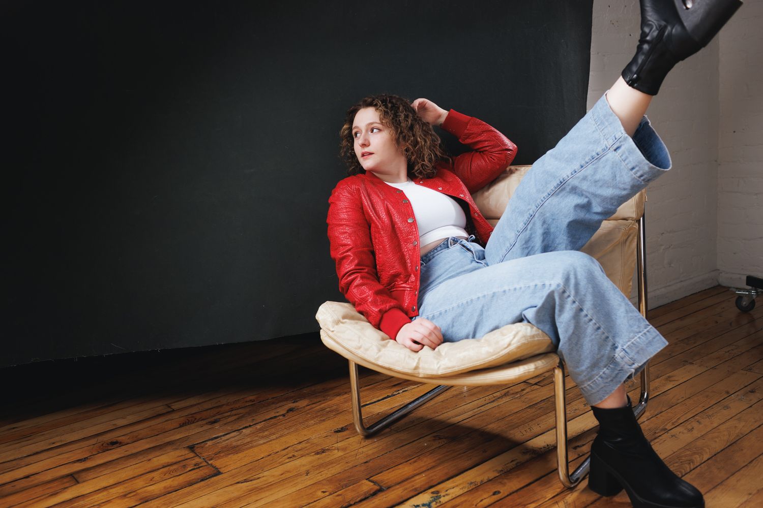 Energetic movement sequence with red jacket and jeans against dark background.