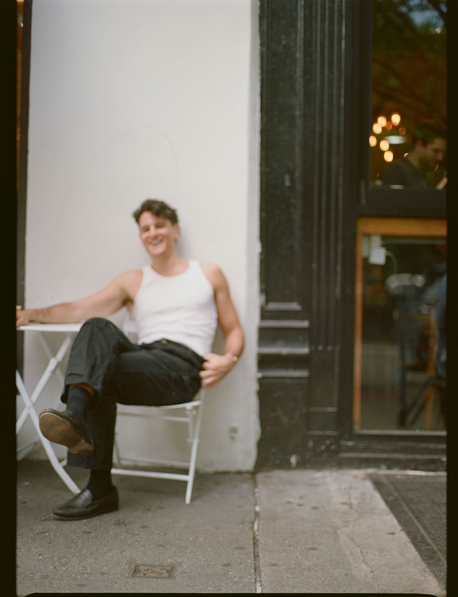 A sequence of four photos showing someone sitting in a white chair against a building wall with a playful pose.