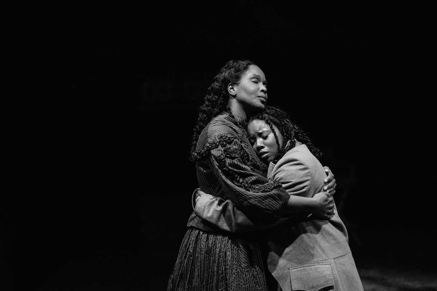 Dramatic black and white performance photos showing dancers in emotional poses and embraces on a dark stage.